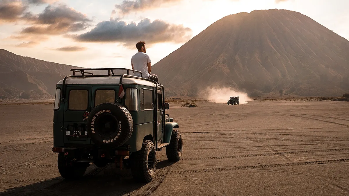 Lautan pasir Bromo yang ikonik di kaldera luas dengan jeep melintas di pasir untuk menuju kawah Gunung Bromo