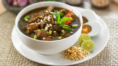 Semangkuk rawon, kuliner legendaris khas Malang berkuah hitam pekat dengan potongan daging, tauge, telur asin, dan jeruk nipis