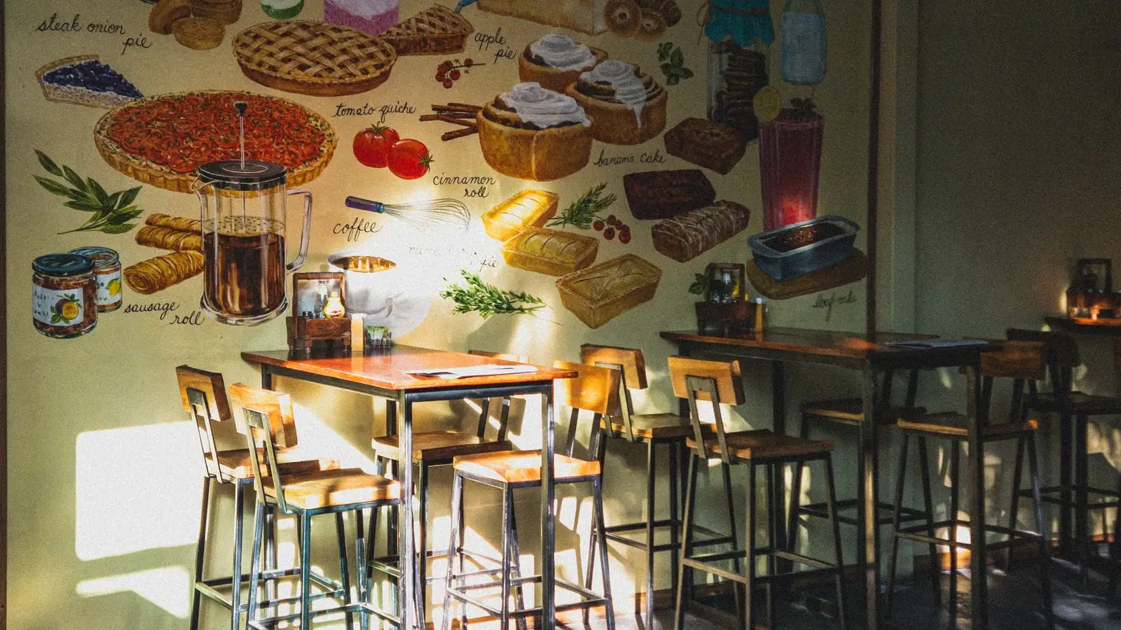 Interior kafe estetik dengan cahaya hangat, mural, dan kursi kayu, suasana nongkrong khas kafe hits Malang