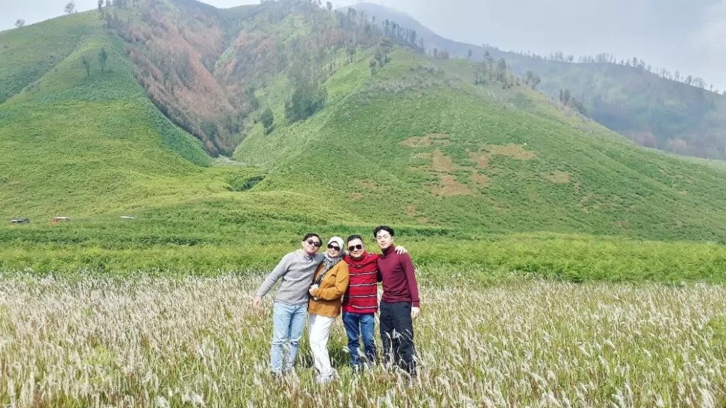 pengunjung berpose dengan latar belakang bukit teletubies, spot ikonik gunung bromo
