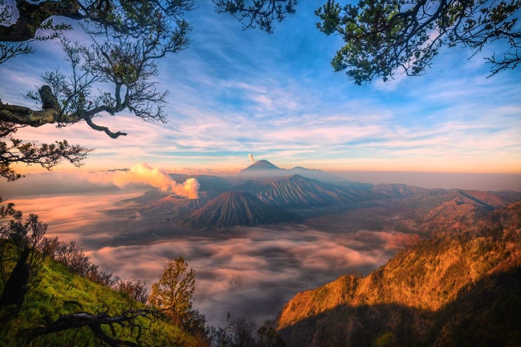 Sunrise Bromo dengan golden sunrise, kabut tipis di kaldera, dan siluet gunung di kawasan Gunung Bromo Jawa Timur